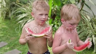 两个小男孩在度假时吃西瓜。 夏天男孩在院子里吃西瓜